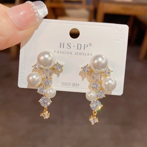 Détail de boucles d'oreilles pompons en perles de luxe avec aiguilles en argent S925
