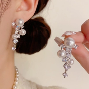 Détail de boucles d'oreilles élégantes à pampilles en perles et zircons brillants