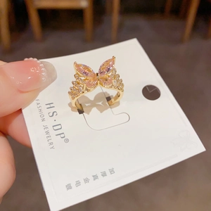 Detalle de anillo de mariposa dorado con gemas rosas y cristales microengastados