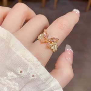 Primer plano de anillo mariposa dorado con circonitas rosas y cristales blancos