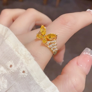Primer plano detallado de un anillo de mariposa dorado con piedras preciosas amarillas