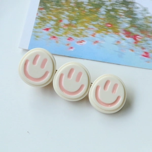 Vue détaillée de la pince à cheveux avec trois disques en résine crème et smileys roses