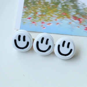 Détail de trois disques sourire en résine blanche sur une barrette en métal doré chic
