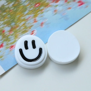 Gros plan d'accessoires ronds en résine blanche avec un motif de smiley noir minimaliste