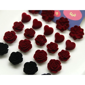Macro detail of flocked velvet rose and heart charms in deep red and black for DIY jewelry
