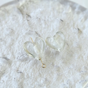 Dettaglio di perle di vetro traslucide a forma di cuore per gioielli fai-da-te con spillo
