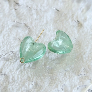 Vista macro di ciondoli a cuore in vetro verde chiaro con foglia d'argento e oro