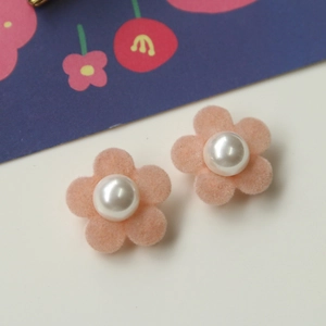 Detailweergave van roze geflokte bloemoorbellen met centrale witte parelaccenten