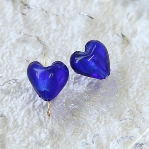 Vista macro di perle a cuore blu traslucido con perno dorato per la creazione di gioielli
