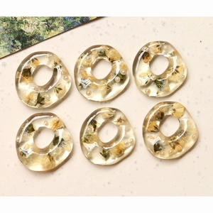 Macro detail of six handmade resin donut charms with real dried flowers and small pearls