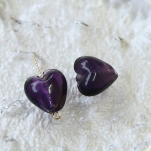 Dettaglio macro di perle in vetro a cuore viola con perni dorati per gioielli fai da te
