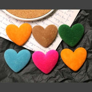 Dettaglio di ciondoli a cuore in velluto colorato su carta nera artistica decorata