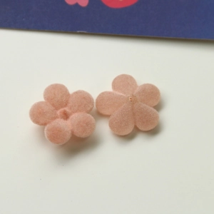 Close-up van roze gevlockte bloembedeltjes van acryl voor DIY-sieraden maken