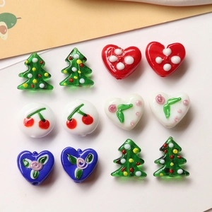 Close-up of glass beads in cherry heart and Christmas tree shapes for DIY jewelry making