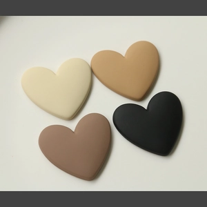 Macro detail of matte heart-shaped charms in cream, tan, brown, and black earth tones