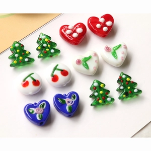 Close-up of assorted glass beads featuring Christmas tree and cherry heart patterns