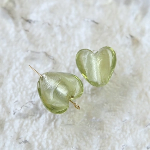 Dettaglio di perle a cuore verde chiaro traslucido con perni dorati per gioielli fai-da-te
