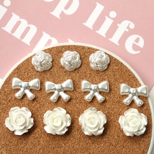 Macro view of pearl white acrylic rose and bow charms for DIY jewelry and hair accessories