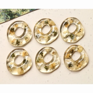 Detailed macro view of 6 handmade resin ring pendants with dried flowers and pearls