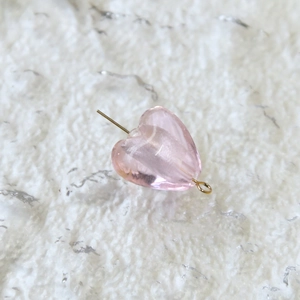 Dettaglio di una perla a cuore rosa traslucido con anello in metallo dorato su pelo bianco