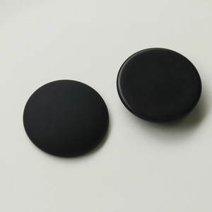 Close-up of black matte circular charms with smooth edges and frosted texture finish