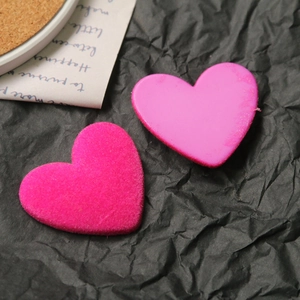 Dettaglio di ciondoli a cuore rosa brillante floccati e lisci per creazioni fai-da-te
