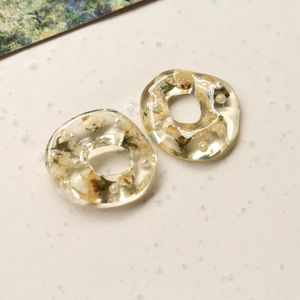 Detailed macro of irregular resin ring featuring embedded dried flowers and pearls