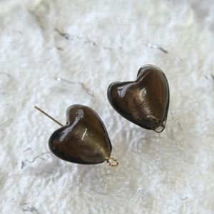 Dettaglio macro di perle di vetro marrone scuro a forma di cuore con glitter dorati