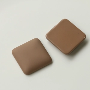 Close-up of matte brown square craft charms with rounded edges for DIY accessories