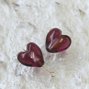 Dettaglio di perle a cuore in vetro magenta con minuterie metalliche dorate per gioielli fai da te