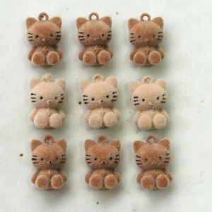 Macro detail of nine flocked kitty charms in milk tea colors for DIY jewelry making