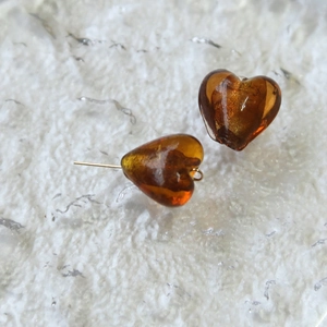 Dettaglio macro di perline a cuore color ambra con perni dorati per creazione di gioielli