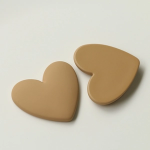 Close-up of matte camel heart-shaped DIY accessories with smooth macaron texture