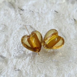 Dettaglio macro di perle di vetro ambrato a forma di cuore con anima dorata per gioielli