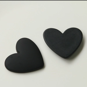 Close-up of matte black semi-circular heart patches for DIY crafts and hair accessories