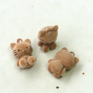 Close-up of three milk tea brown flocked kitten charms for DIY crafts and jewelry making