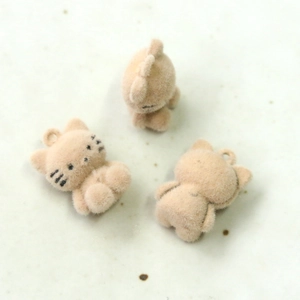 Detailed macro view of cute flocked cat charms for DIY jewelry and crafts in beige