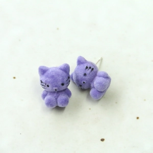 Primer plano detallado de pendientes de gato flocados en violeta con textura suave y dulce