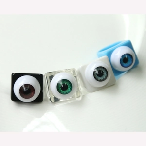 Detailed close-up of four square resin eyeball rings in black, clear, white and blue
