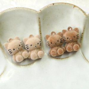 Macro detail of plush 3D cat charms in milk tea colors for DIY jewelry making