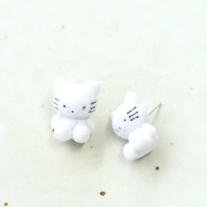Detalle de pendientes de gato 3D blancos flocados con suave textura de felpa sobre piedra