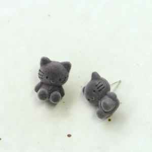 Detalle de pendientes de gato flocados grises con agujas de plata sobre cerámica