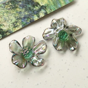 Detail of translucent iridescent resin daisy charms with green centers for DIY jewelry making