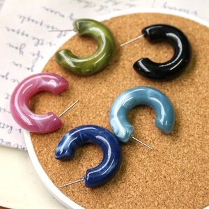 Detail of C-shaped acrylic earrings with marble texture in multiple soft ink colors