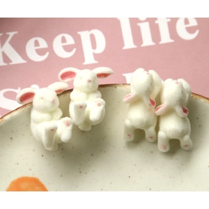 Detail of four flocked mini white bunny figurines with soft texture for DIY jewelry crafts