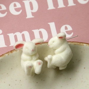 Macro shot of flocked rabbit stud earrings with soft texture on a ceramic dish