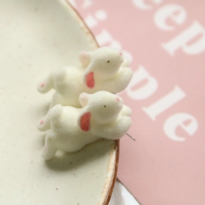 Charming white flocked bunny earrings with pink accents displayed on a ceramic tray