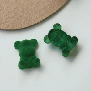Detail view of green flocked and resin teddy bear charms for DIY jewelry accessories
