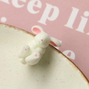 Detailed view of miniature white flocked rabbit resin charm with soft pink ear details