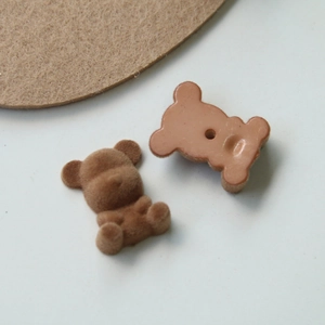 Macro shot of flocked teddy bear DIY accessory showing brown texture and back slot detail
